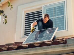 brandverzekering zonnepanelen. Man plaatst zonnepaneel op dak